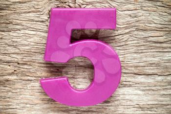 Purple number five on the wooden background