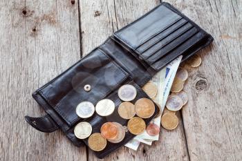 Open wallet with euro currency on the wooden background