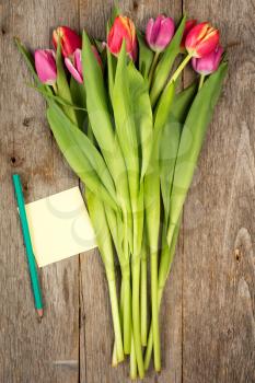  Tulip bouquet and blank sticky note on a wooden planks
