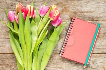 Tulip bouquet and spiral notebook on a wooden planks