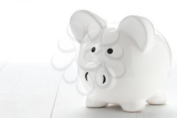 Piggy bank on white wooden floor. Copy-space.