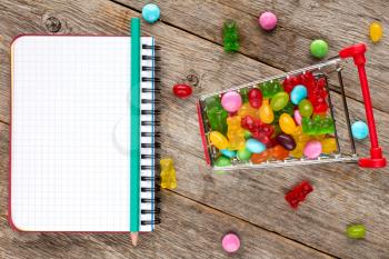 Blank notebook and shopping cart full of candies