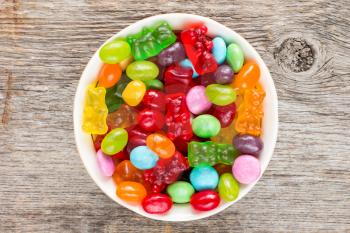 Bowl full of colorful candies on the wooden background