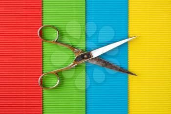 Old scissors on colored corrugated paper background.