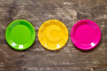 Green, yellow and pink color plates set  on wooden background