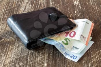 Black leather  wallet with euro banknotes on the wooden table