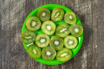 Fruit kiwi slices in a green plate, top view