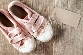 Kids shoes with blank tag on a wooden background