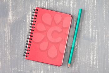 Spiral notebook and pencil over grey wooden background.Copy-space.