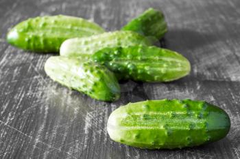  Green cucumbers on a grey wooden background.