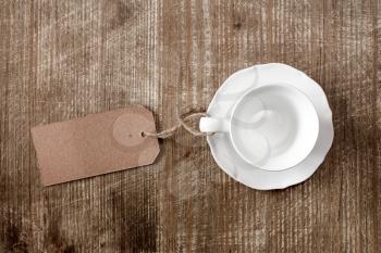 White empty cup with paper blank tag on wooden background
