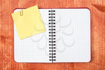 Open notebook with sticky note on red wooden background
