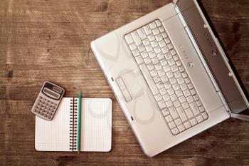 Top view working desk with laptop computer, calculator and spiral notebook