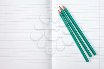 Lined exercise book and three pencils. Back to school concept.