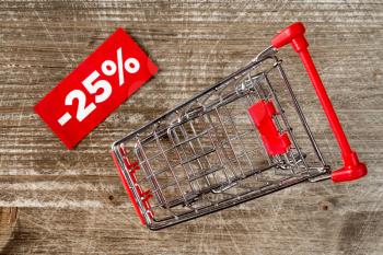 Shopping cart with tag of discount or sale,on the wooden background. Top view.