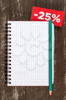 Blank notebook with tag of discount or sale,on the wooden background. Top view.
