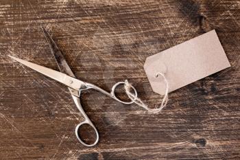 Metal scissors with blank tag on wooden desk