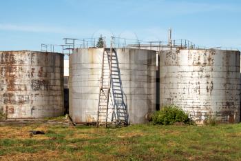 Old industrial storage tank with stairs against a blue sky