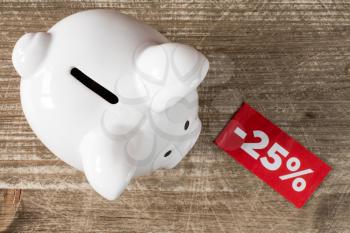 Piggy-bank with tag of discount or sale,on the wooden background. Top view.