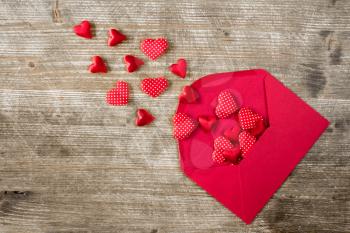 Open envelope with red hearts on the wooden background