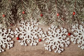 Wooden background with fir branch and silver shiny snowflakes 