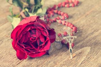 Rosary and old rose on wooden background
