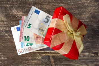 Gift Box with Euro currency on the wooden background