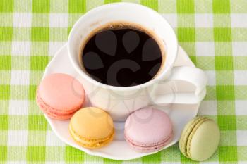 Cup of black coffee with colorful french macaroons