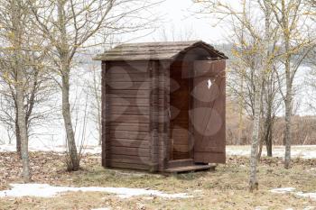 Wooden toilet with opened door in the park