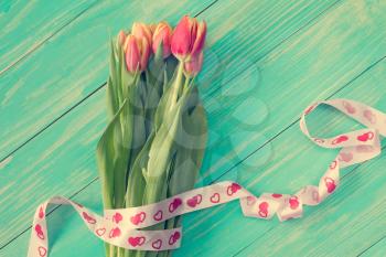 Tulips bouquet with ribbon on blue wooden background