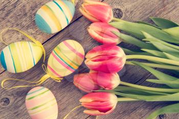 Easter eggs and blooming tulips on wooden background