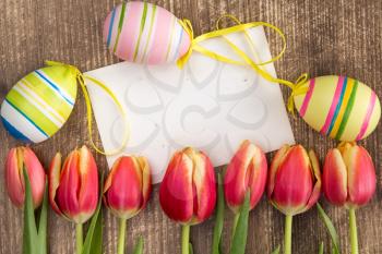 Easter eggs,blank card and fresh spring tulips on wooden background