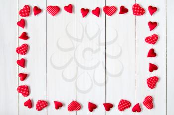 Frame of hearts on a white wooden background