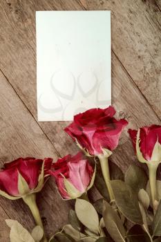 Four red roses and blank card for copy-space