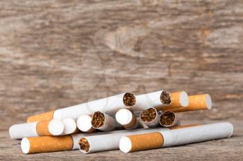 Pile of cigarettes scattered on wooden background