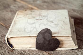 Old book with paper heart on wooden background. Passion for reading.