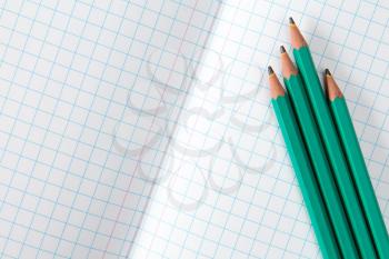 Squared exercise book and four pencils. Back to school concept.
