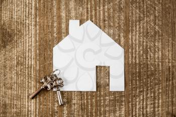 House icon and keys on wooden background. Real estate concept.