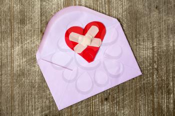 Envelope with broken heart on wooden table 