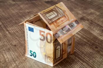 House made of fifty Euro banknotes on a wooden background