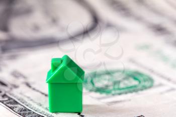 Miniature house on dollar banknote background. Concept for property ladder, mortgage and real estate investment