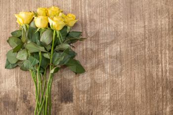 Bouquet of yellow roses with copy space on wooden background