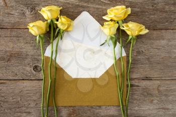 Yellow roses and love letter or note card with golden envelope