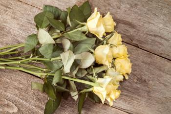 Bouquet of yellow roses on wooden background, top view