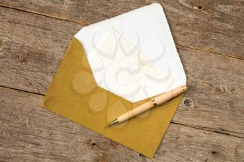 Golden envelope, blank card and pen on wooden background