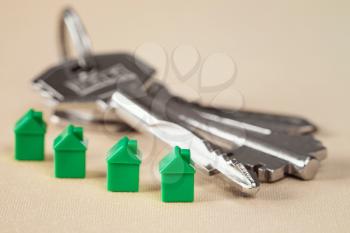 Green miniature houses and bunch of keys. Real estate concept.