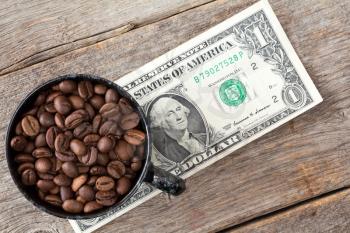 Cup of coffee beans on dollar banknote represent high or low price of coffee on stock market