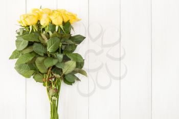 Bouquet of yellow roses with copy space on white wooden background