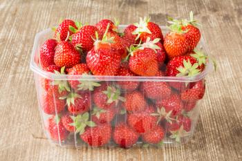 Symbol of summer, a punnet of delicious fresh strawberries on wooden table