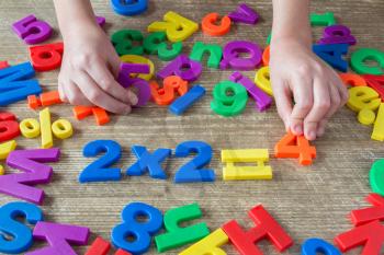 Child's hands playing with numbers, learning simple multiplication